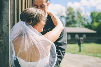 A groom wiping a tear during the ceremony, framed by rustic wooden beams.