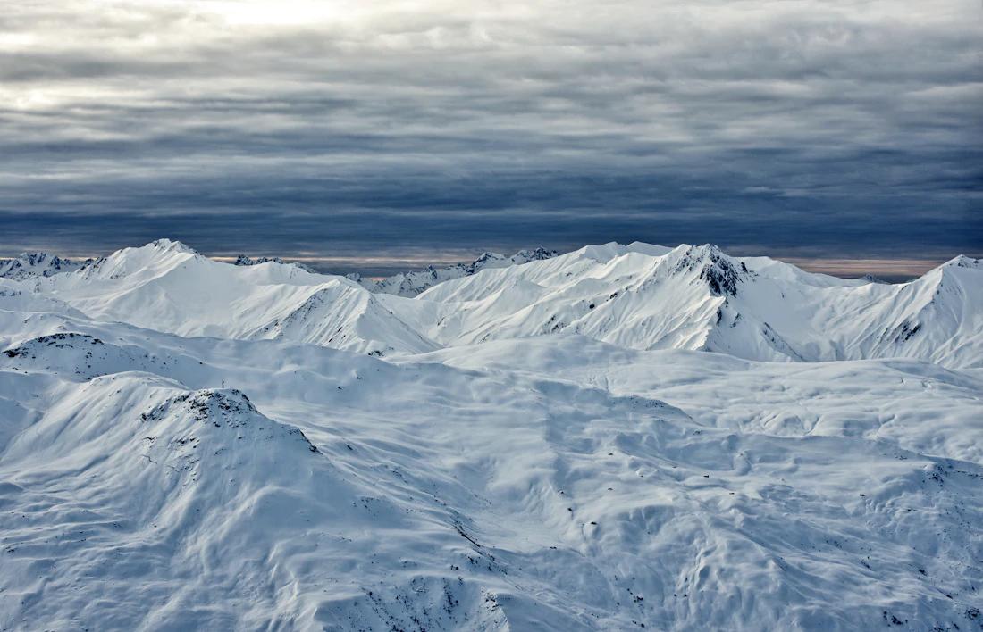 Donkere wolken boven besneeuwde bergen bij Les Menuires