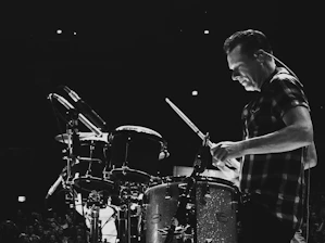 Warm close-up of a drummer's hands passionately playing a snare drum in a cozy studio.