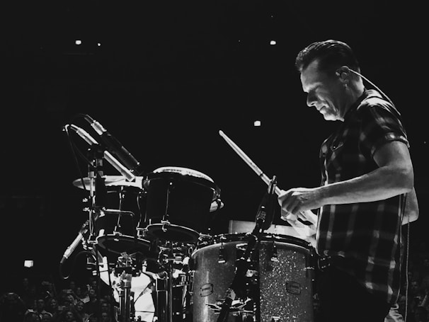 A drummer energetically performing with a spotlight on them.
