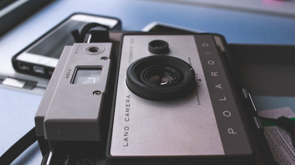 gray Polaroid land camera on table near white Android smartphone