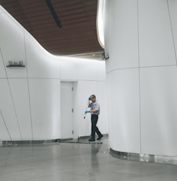 man cleaning on floor beside white wall