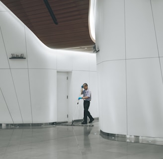 man cleaning on floor beside white wall