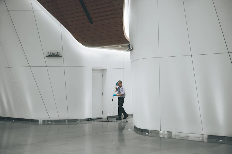 man cleaning floor beside white wall
