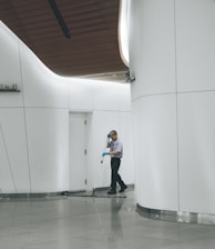 man cleaning on floor beside white wall