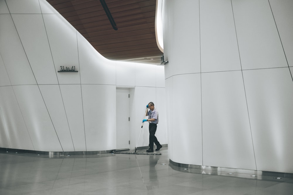 man cleaning on floor beside white wall