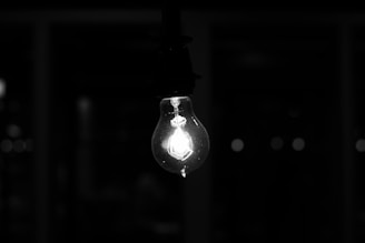 A glowing lightbulb illuminating a dark room, symbolizing sudden insight and breakthrough ideas.