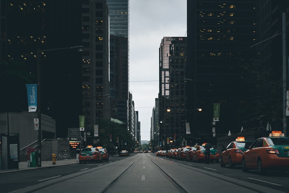 Foto von orangefarbenen Taxis, die auf dem Bürgersteig in der Nähe von Gebäuden geparkt sind