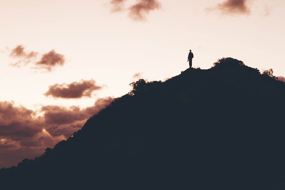 foto do homem em pé no topo da montanha