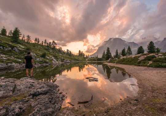 man stands on rock beside body of water during day in Passo Falzarego Italy