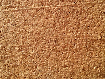 A close-up view of a cork board, characterized by its rough, textured surface and natural brown tones. The image highlights the irregular patterns and grain structure of the cork material.