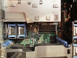 A detailed view of a server's internal components, including multiple RAM slots, visible circuit boards, and several connected hardware elements like hard drive bays and cooling fans. The interior is organized with cables and components aligned neatly inside the chassis.
