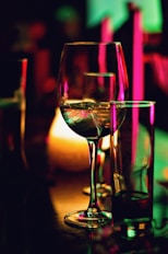 half filled wine glass beside half empty clear pint glass