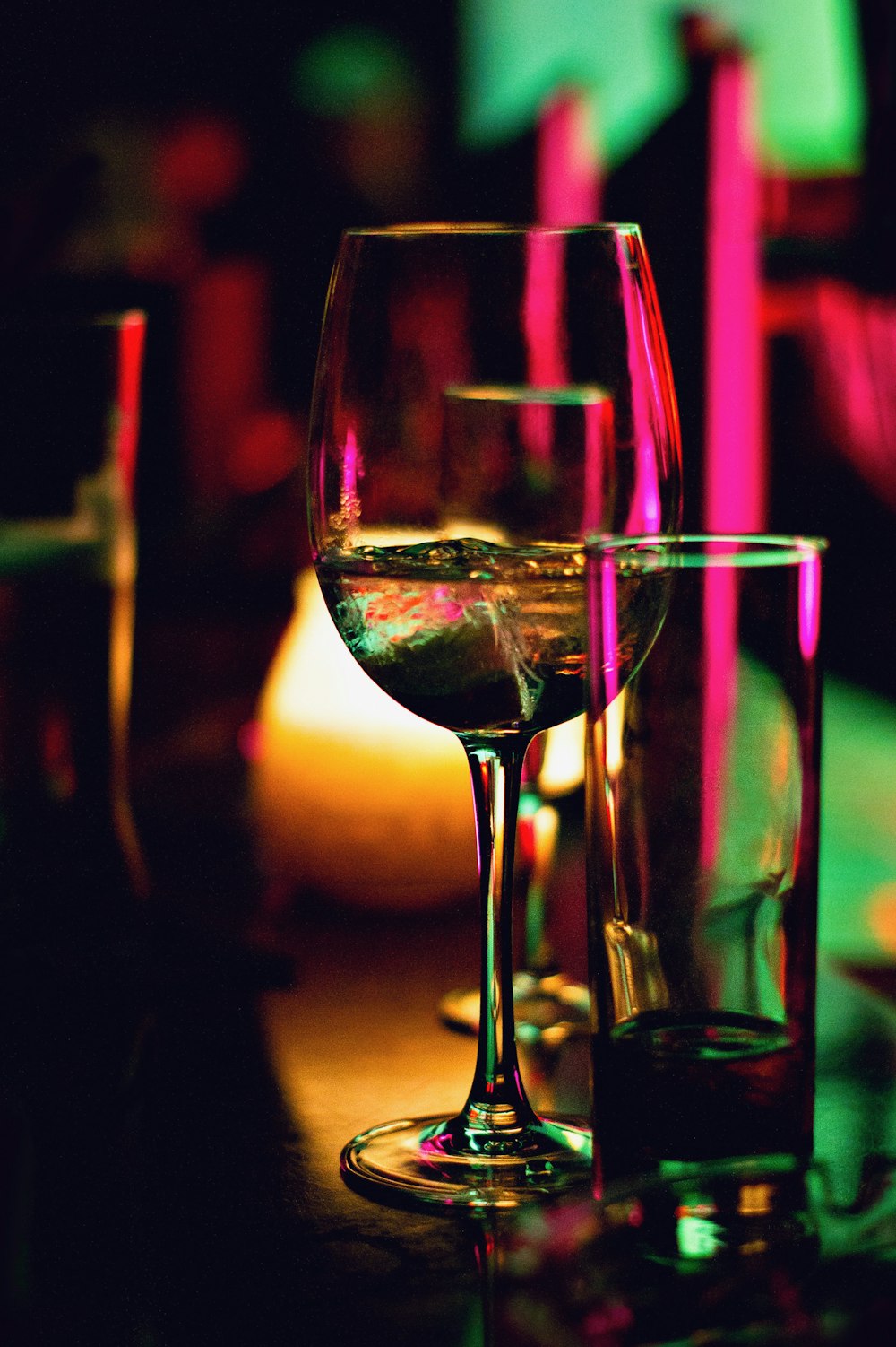 Copa de vino medio llena junto a una copa de pinta transparente medio vacía