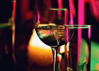 half filled wine glass beside half empty clear pint glass