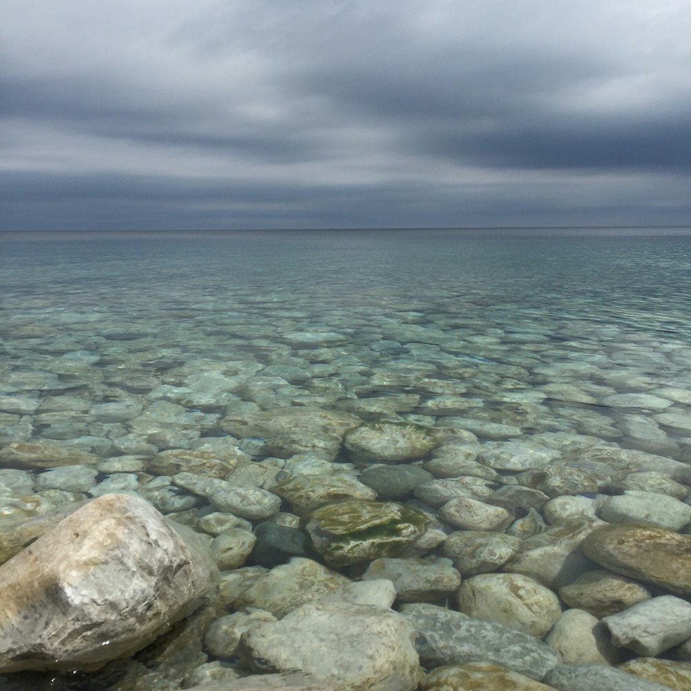 plan d’eau avec des pierres sous ciel nuageux