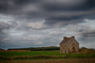 A weathered Scottish farmhouse at dawn with mist curling over the fields.