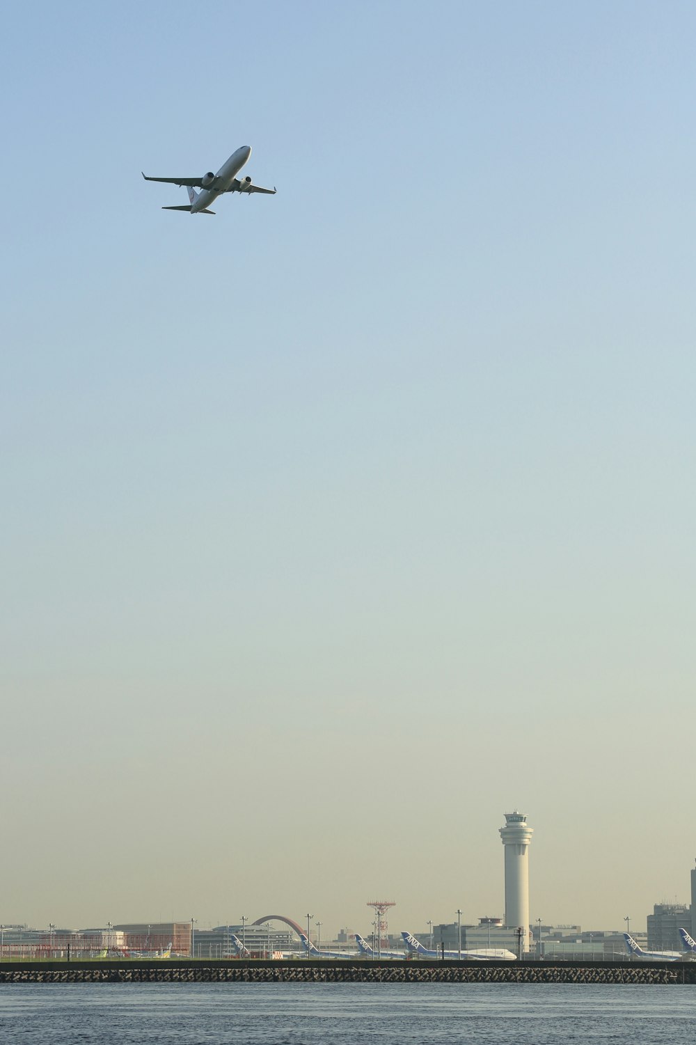 white airplane in sky above body of water