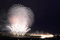 A serene moment with glowing fireworks reflecting over a calm water surface.