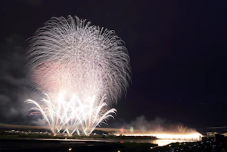 A serene moment with glowing fireworks reflecting over a calm water surface.