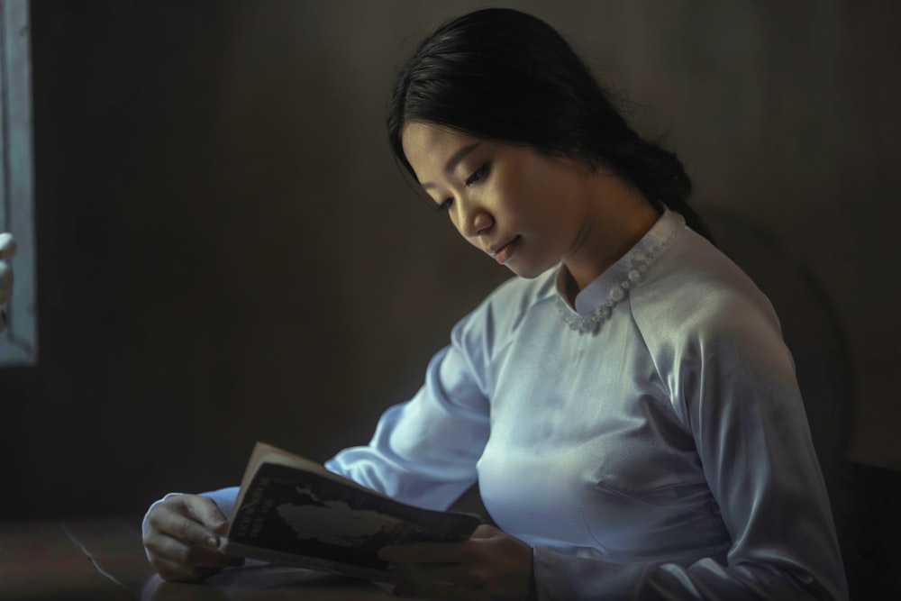 woman wearing gray long-sleeved tops reading book