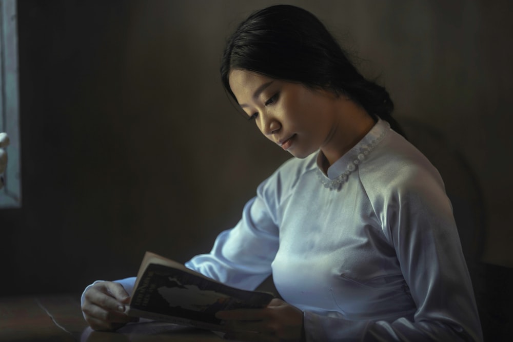 灰色の長袖トップスを着て本を読む女性