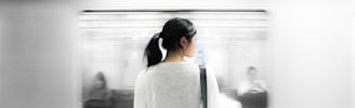 woman in white elbow-sleeved shirt standing near white train in subway