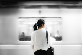 woman in white elbow-sleeved shirt standing near white train in subway