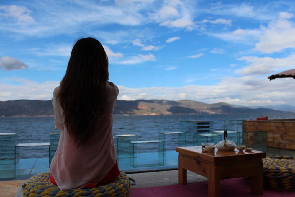 woman in white top sitting in front of mountain