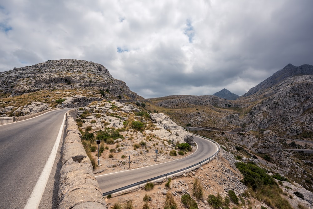 road near mountains under clouds