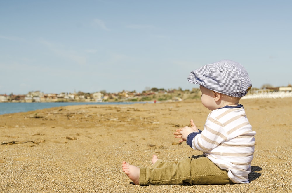 criança sentada na praia durante o dia