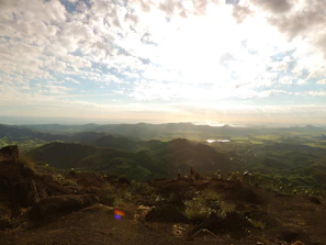 Panoramic view from a summit showing rolling hills and distant peaks bathed in golden afternoon light