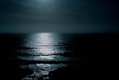 body of water under cloudy sky at night