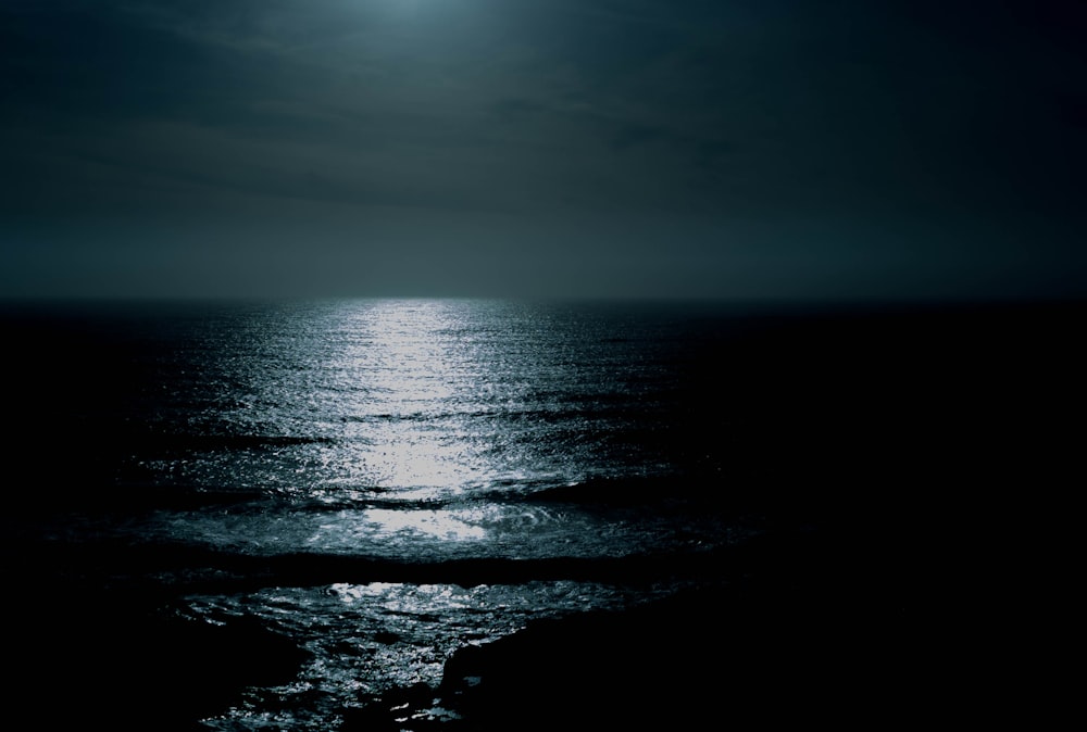 body of water under cloudy sky at night