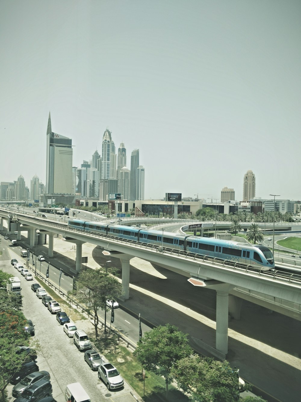 blue train near high-rise buildings under gray sky at daytime