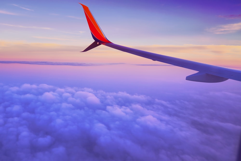 Person in einem Flugzeug, das in großer Höhe fliegt, macht tagsüber ein Foto des linken Flugzeugflügels