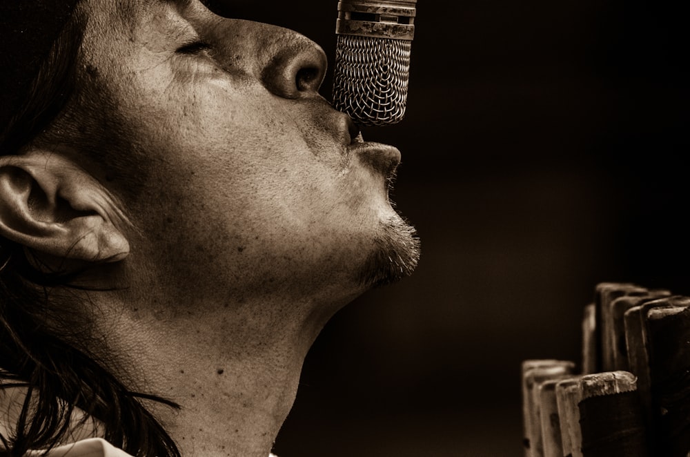 hombre cantando con la fotografía en escala de grises del micrófono