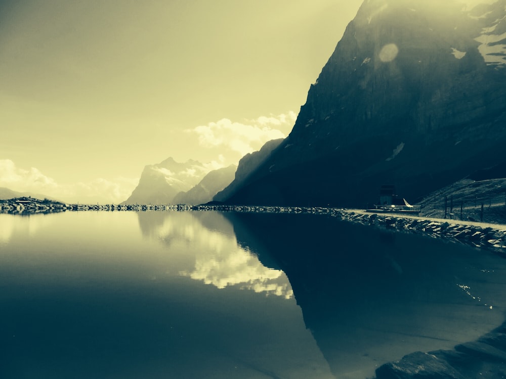 low-light photo of calm body of water in front of mountain