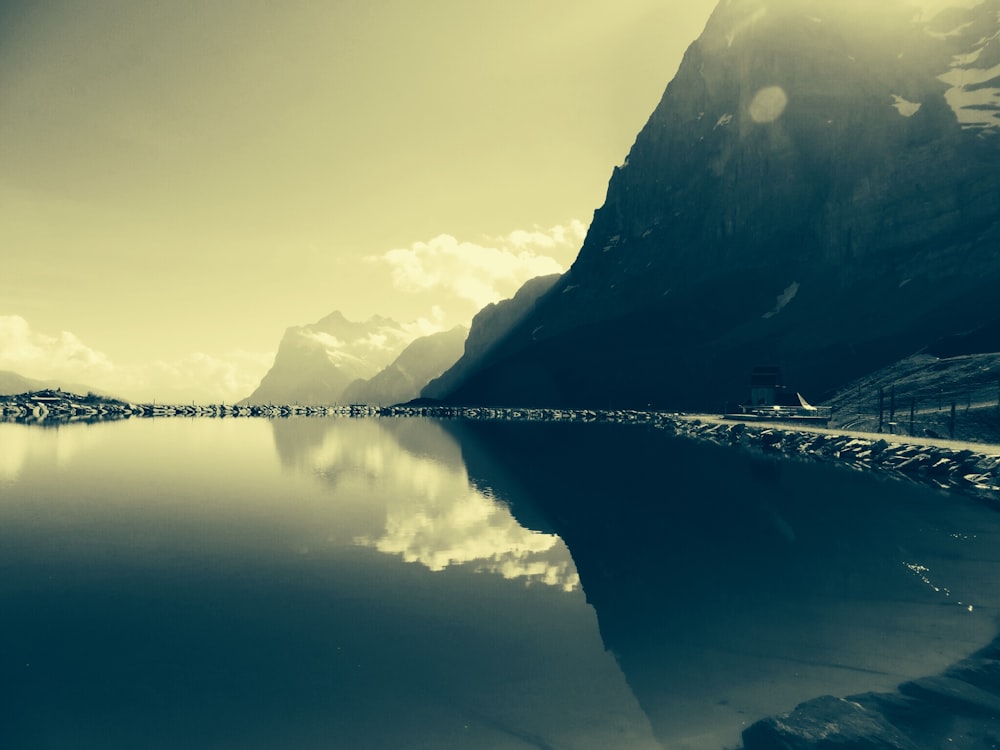 Foto con poca luz de un cuerpo de agua tranquilo frente a la montaña