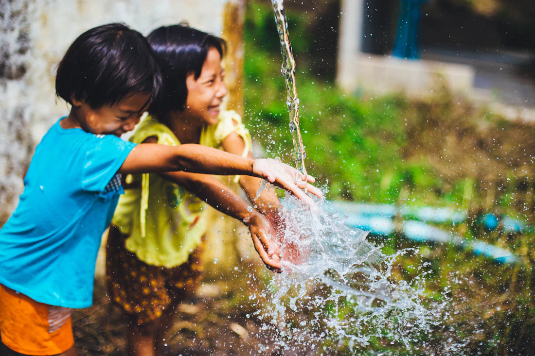 Two girls laughing as they splash in clear water