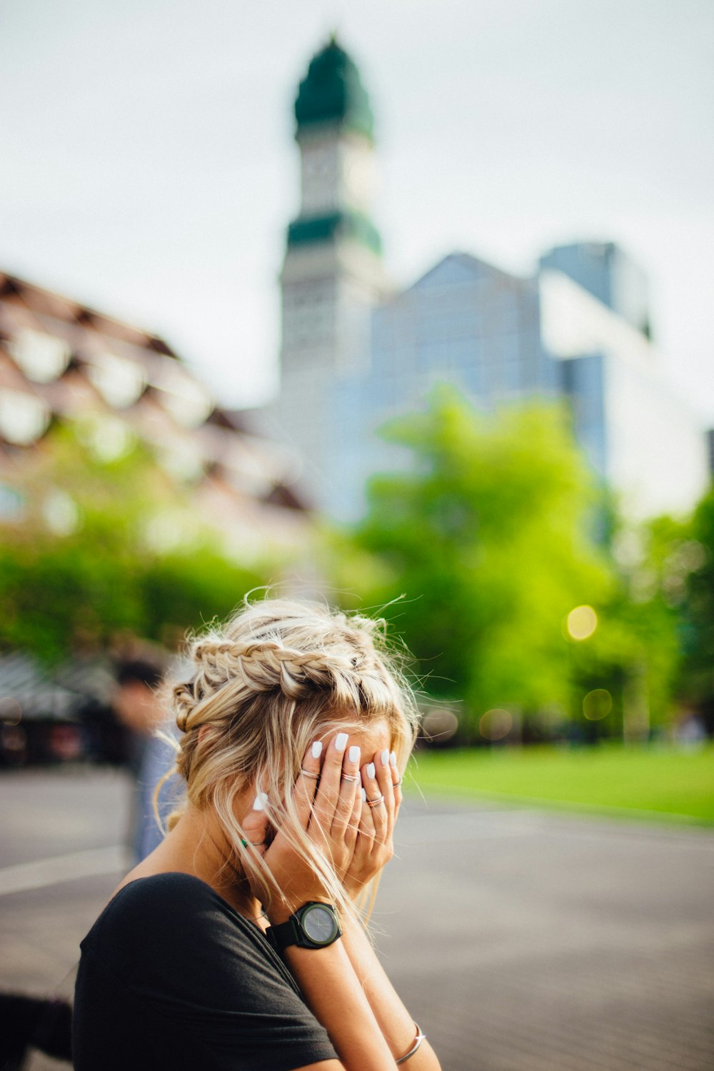 person covering face with hands outdoors