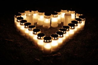 Soft glowing candles surrounding a heart-shaped arrangement of herbs and flowers.