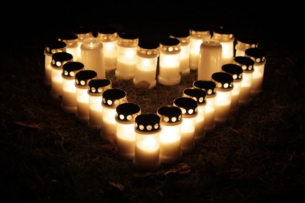 Soft glowing candles surrounding a heart-shaped arrangement of herbs and flowers.