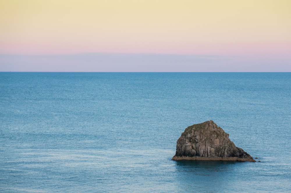 gray rock in the middle of calm body of water