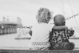 grayscale photography of two children sitting on ledge