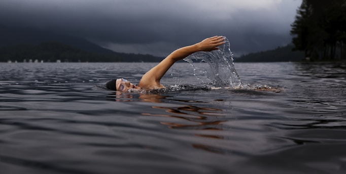 man swimming on body of water