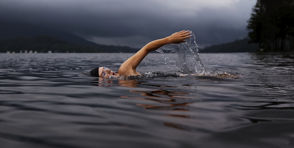 man swimming on body of water