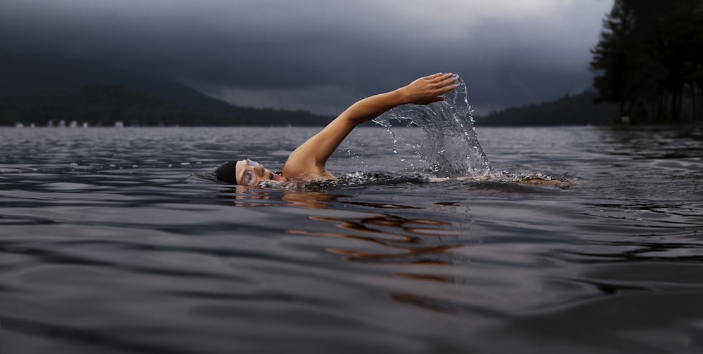 homem nadando no corpo de água