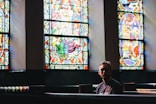 man sitting on pew chair