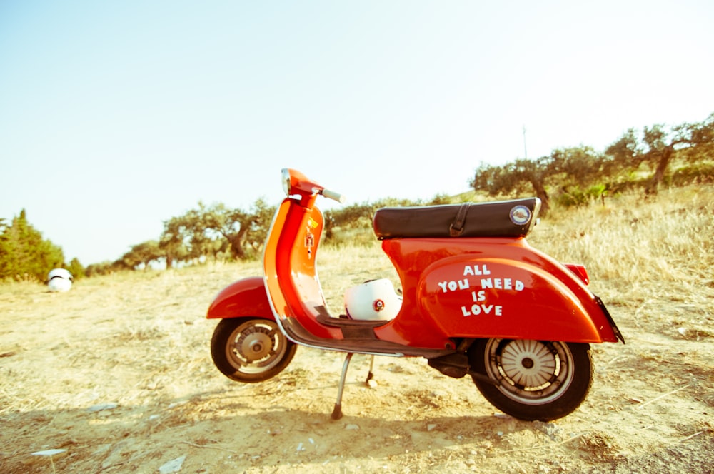 scooter rojo y negro en campo abierto bajo cielo azul claro